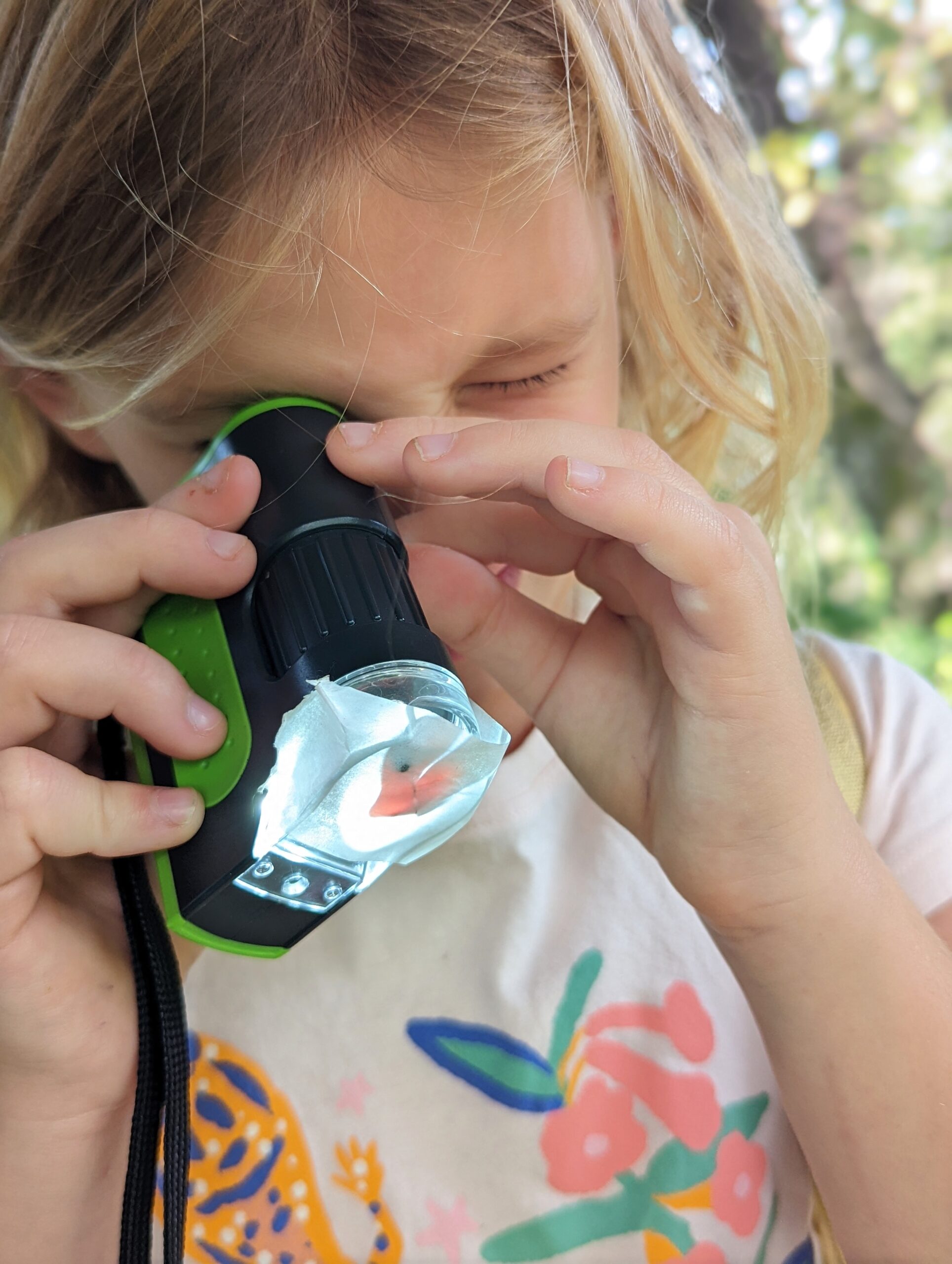girl looking through a microscope in nature